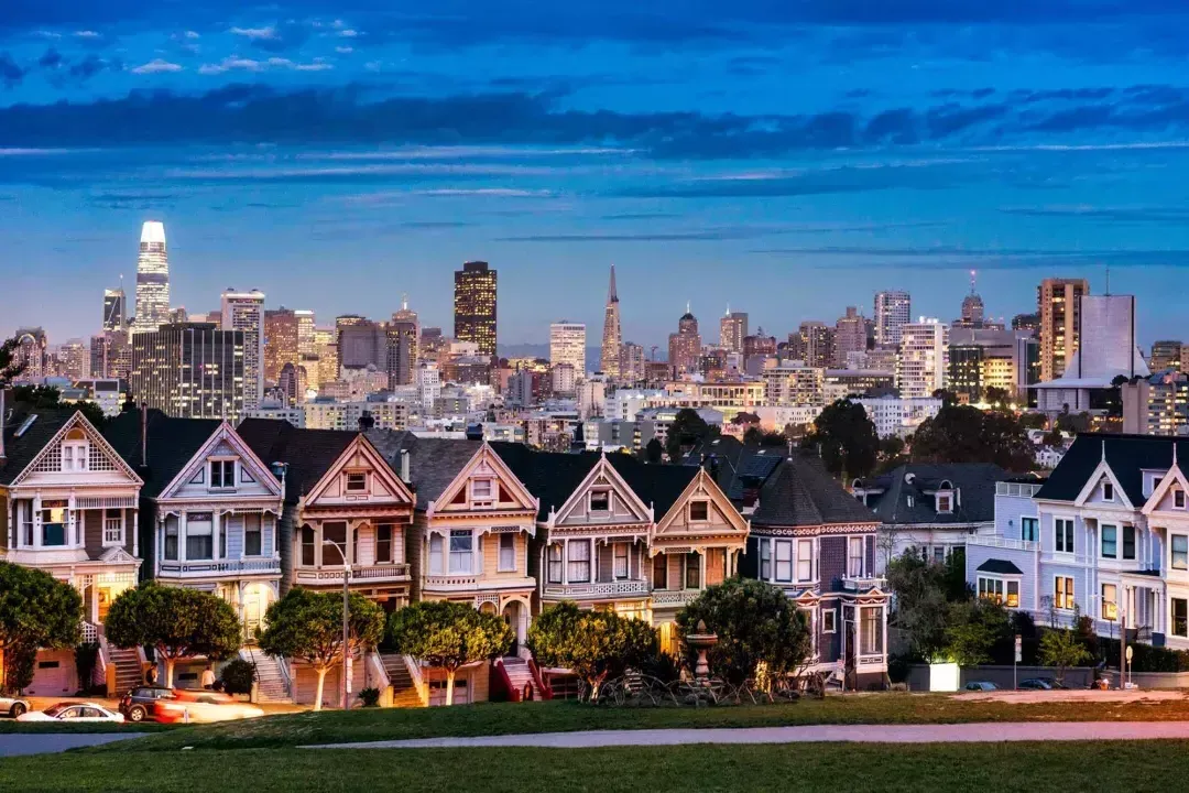 Les célèbres Painted Ladies d'Alamo Square sont photographiées devant l'horizon de San Francisco au crépuscule.