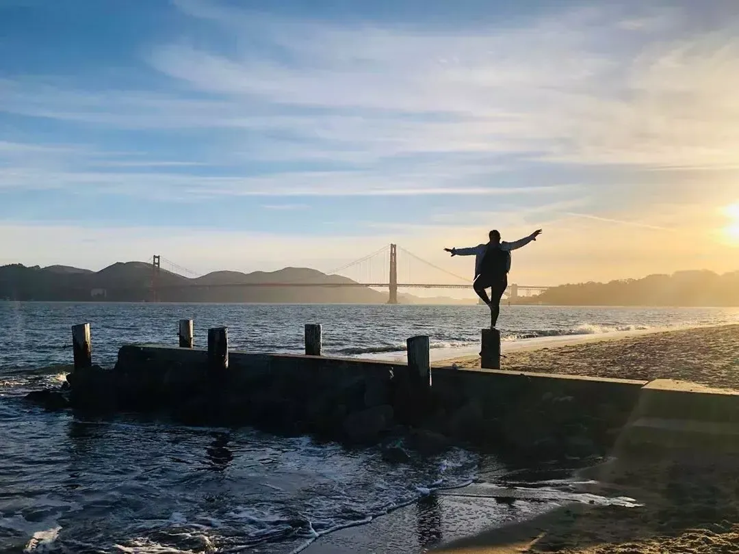 Une femme se tient sur une jetée du quartier Marina de San Francisco, face au Golden Gate Bridge.